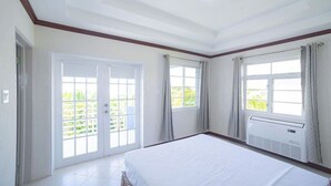 Une chambre d’hôtel avec un grand lit, des portes-fenêtres coulissantes donnant sur un balcon et une fenêtre avec des rideaux.