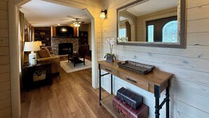 Un interior de madera con chimenea, televisión y espejo.