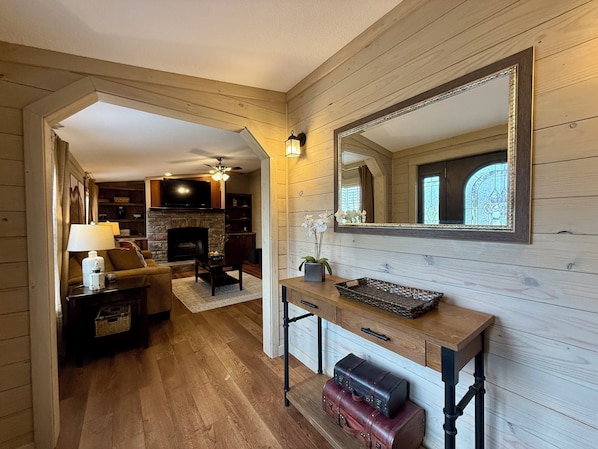Un interior de madera con chimenea, televisión y espejo.
