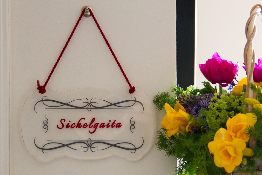 A sign with the name "Sicholgaite" hanging on a wall, next to a floral arrangement.