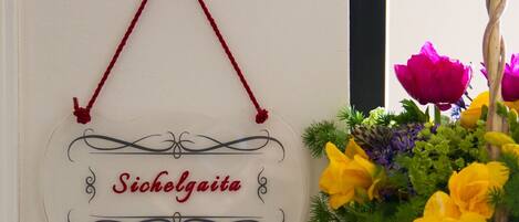 A sign with the name "Sicholgaite" hanging on a wall, next to a floral arrangement.