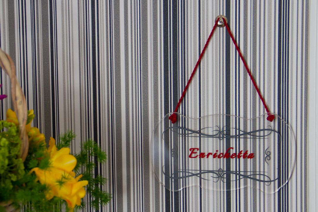 Un letrero decorativo y llamativo con la palabra "Enrichetto" sobre un fondo a rayas.