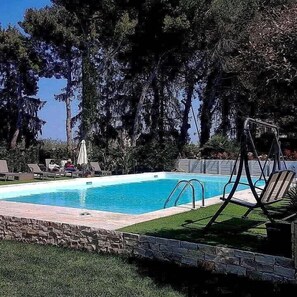 A swimming pool with lounge chairs and umbrellas, surrounded by trees. - Le Duchesse Rooms and Events (Trani)