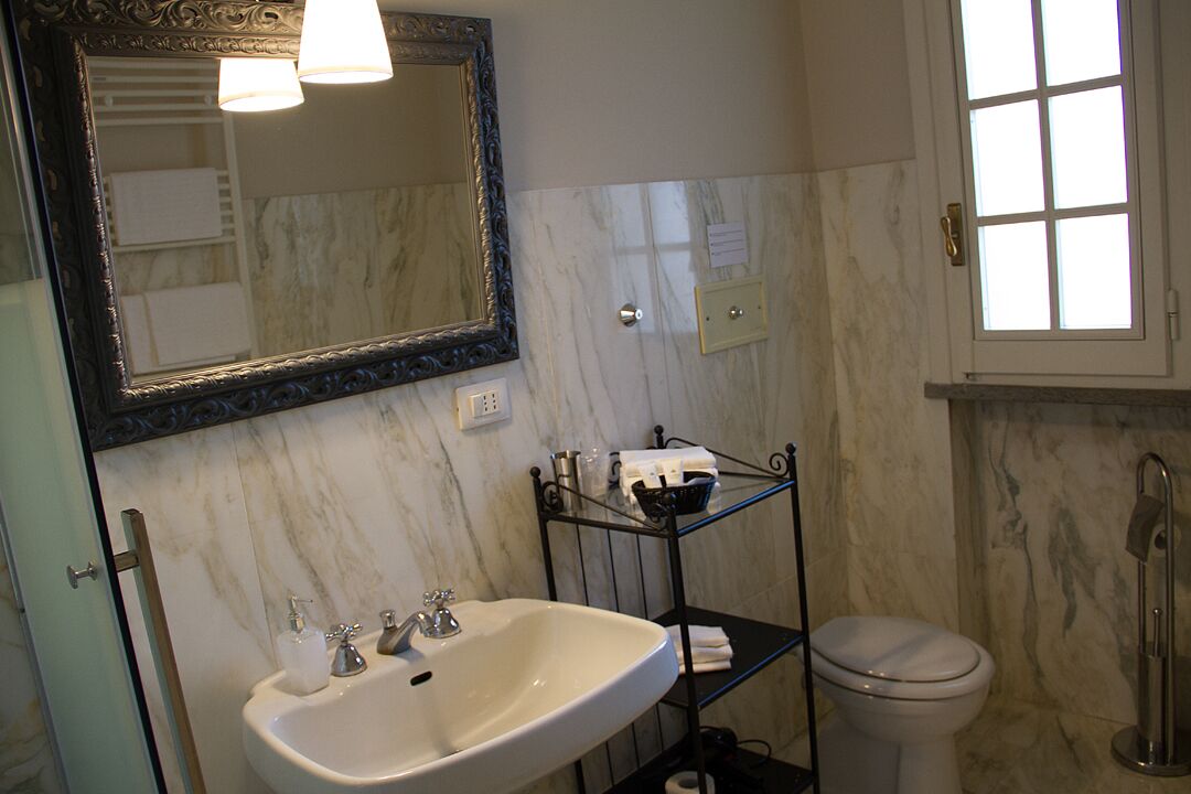 A bathroom with a white sink, a toilet, a mirror, and a window.