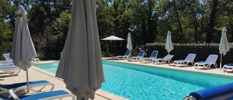 Ein Schwimmbad mit Liegestühlen und Sonnenschirmen.