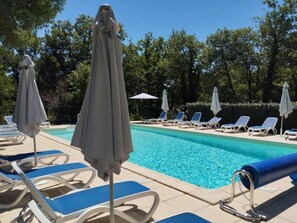 Una piscina con sillones de descanso y sombrillas.