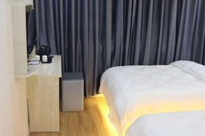 A hotel room with a bed, a bedside table, a lamp, and a curtain. - Yijia Hotel (Shanghai Jinshan New Town Wanda Plaza) (Shanghai)
