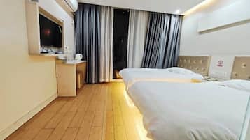 Quarto de hotel com duas camas, televisão, mesa com cafeteira e janela com cortinas.