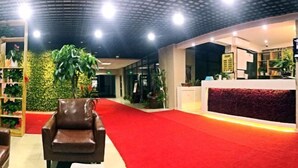 A reception area with a red carpet, a reception desk, and a seating area with a brown chair. - Yijia Hotel (Shanghai Jinshan New Town Wanda Plaza) (Shanghai)