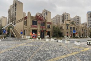 A multi-story building with a prominent entrance, a ramp, and a paved plaza in front. - Yijia Hotel (Shanghai Jinshan New Town Wanda Plaza) (Shanghai)
