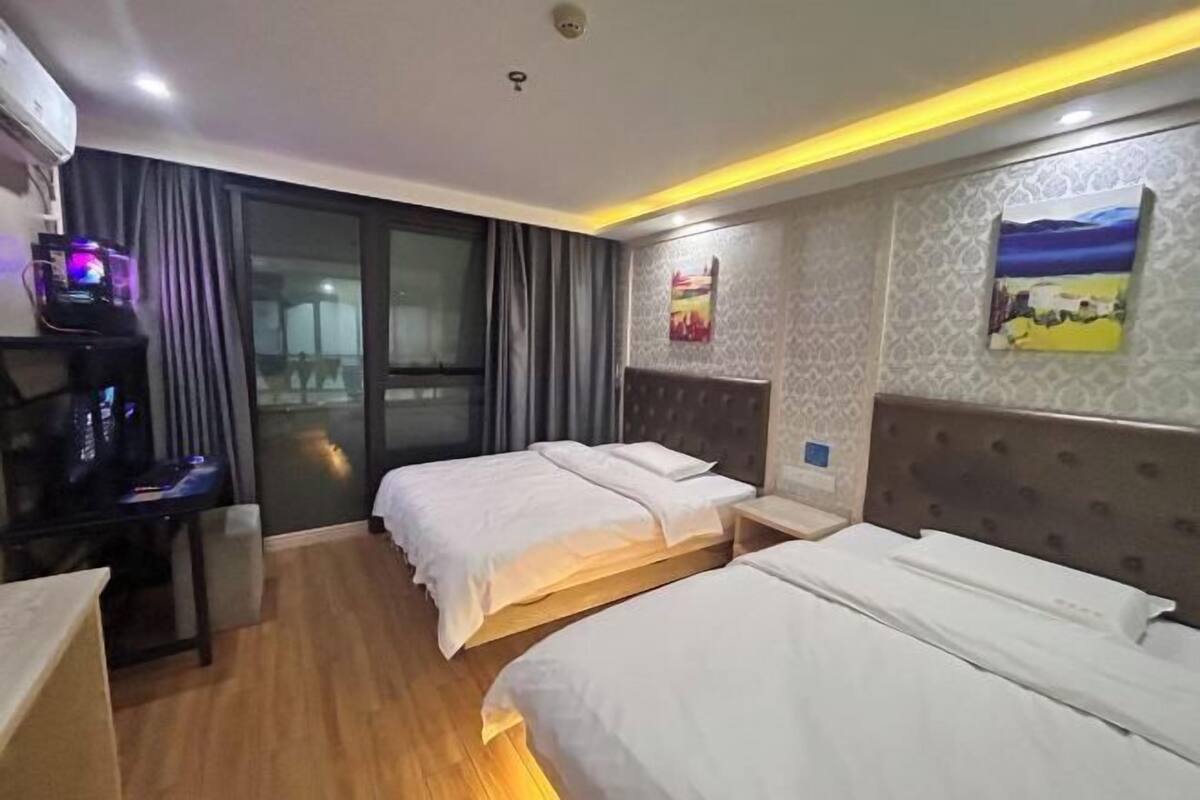 Ein Hotelzimmer mit zwei Betten, einem Schreibtisch mit einem Computer und einem großen Fenster.