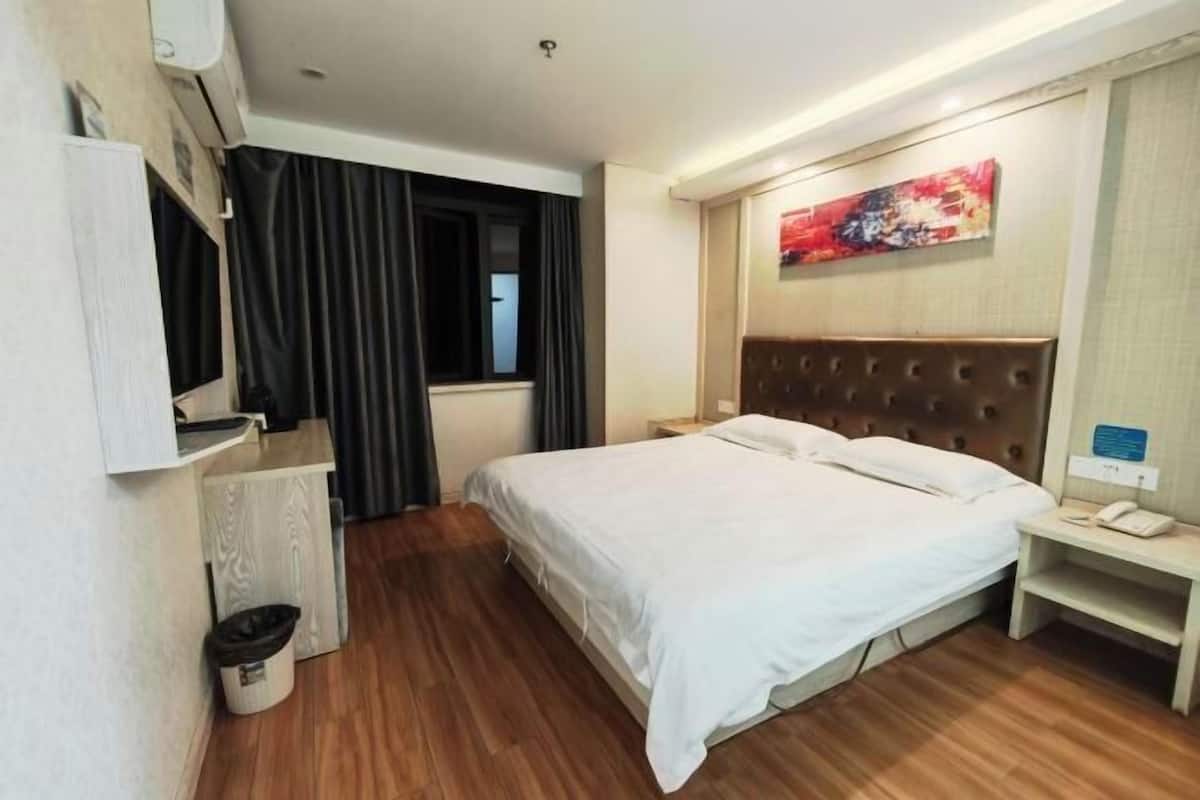 Ein Hotelzimmer mit Bett, Nachttisch, Lampe und einem Gemälde an der Wand.