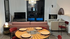 A dining area with a round wooden table, red chairs, and a hanging light fixture. - Air-conditioned villa with pool and panoramic sea view, 6 pax (Brando)