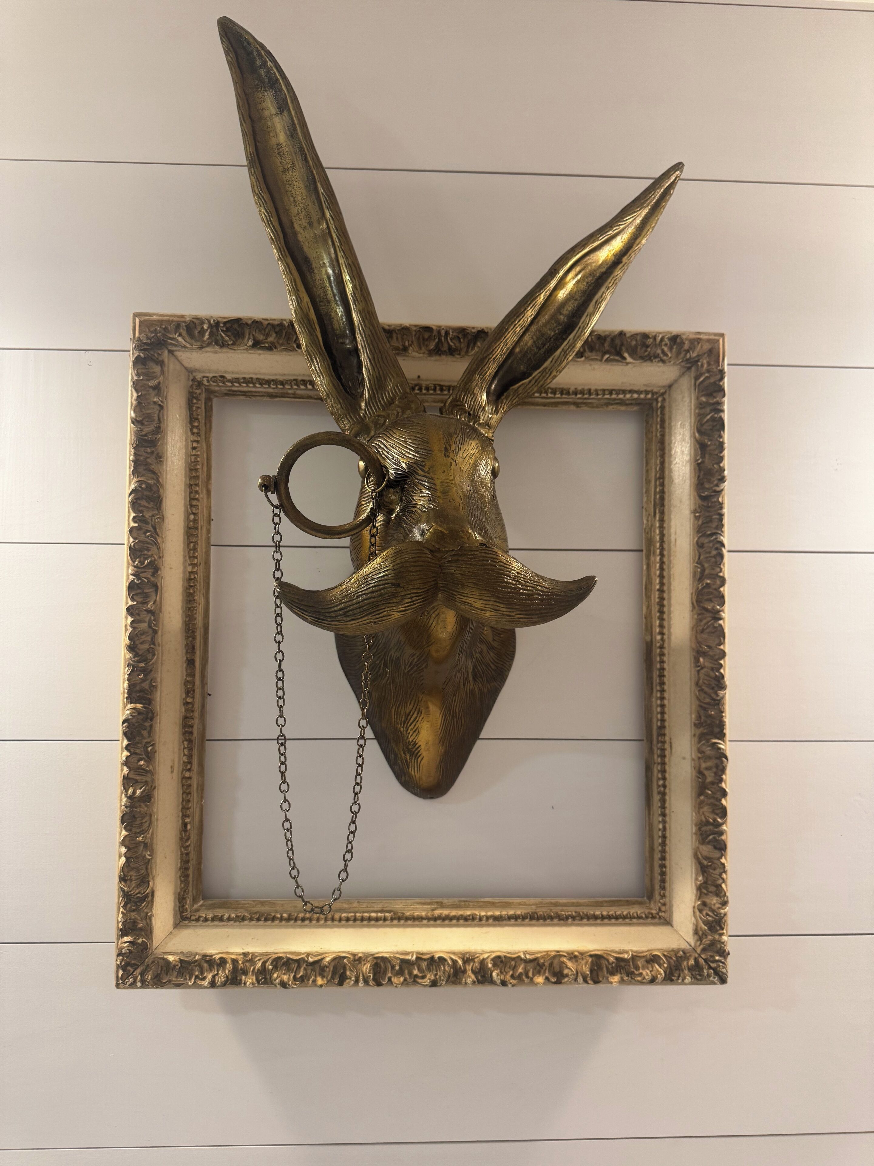 A framed animal head with horns and a chain, mounted on a wall.