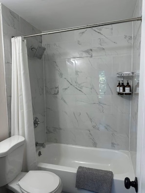 A bathroom with a shower, toilet, and a towel rack.