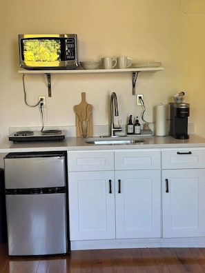 A kitchenette with a microwave, coffee maker, and a refrigerator.