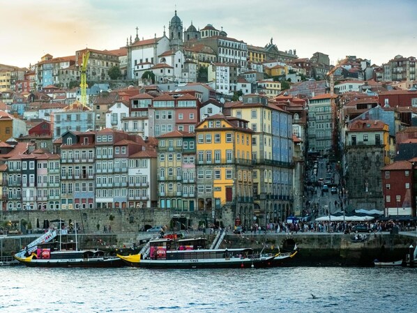 Un paisaje urbano frente al agua con edificios de colores, una iglesia destacada y un ferry atracado en el muelle.