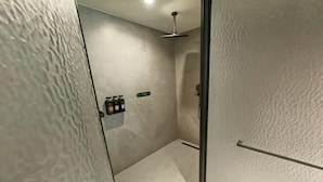 Une salle de bain moderne équipée d’une douche, d’un porte-serviettes et d’une étagère pour les articles de toilette.