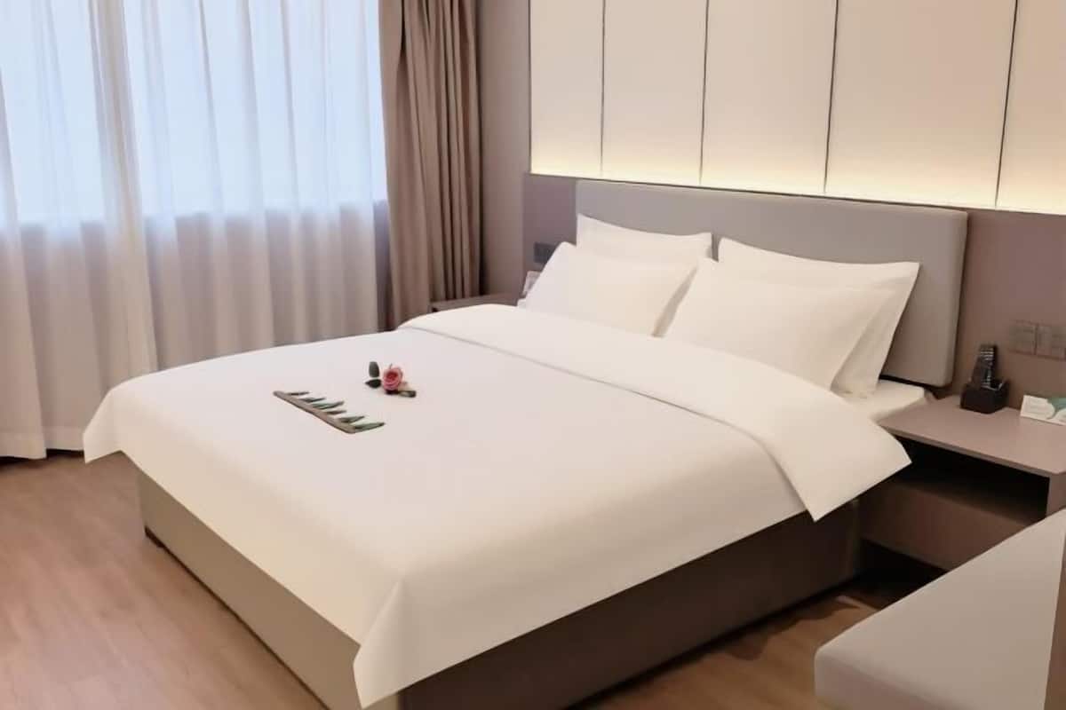Una camera d'albergo con un letto grande, un comodino e un tavolino di fianco al letto.