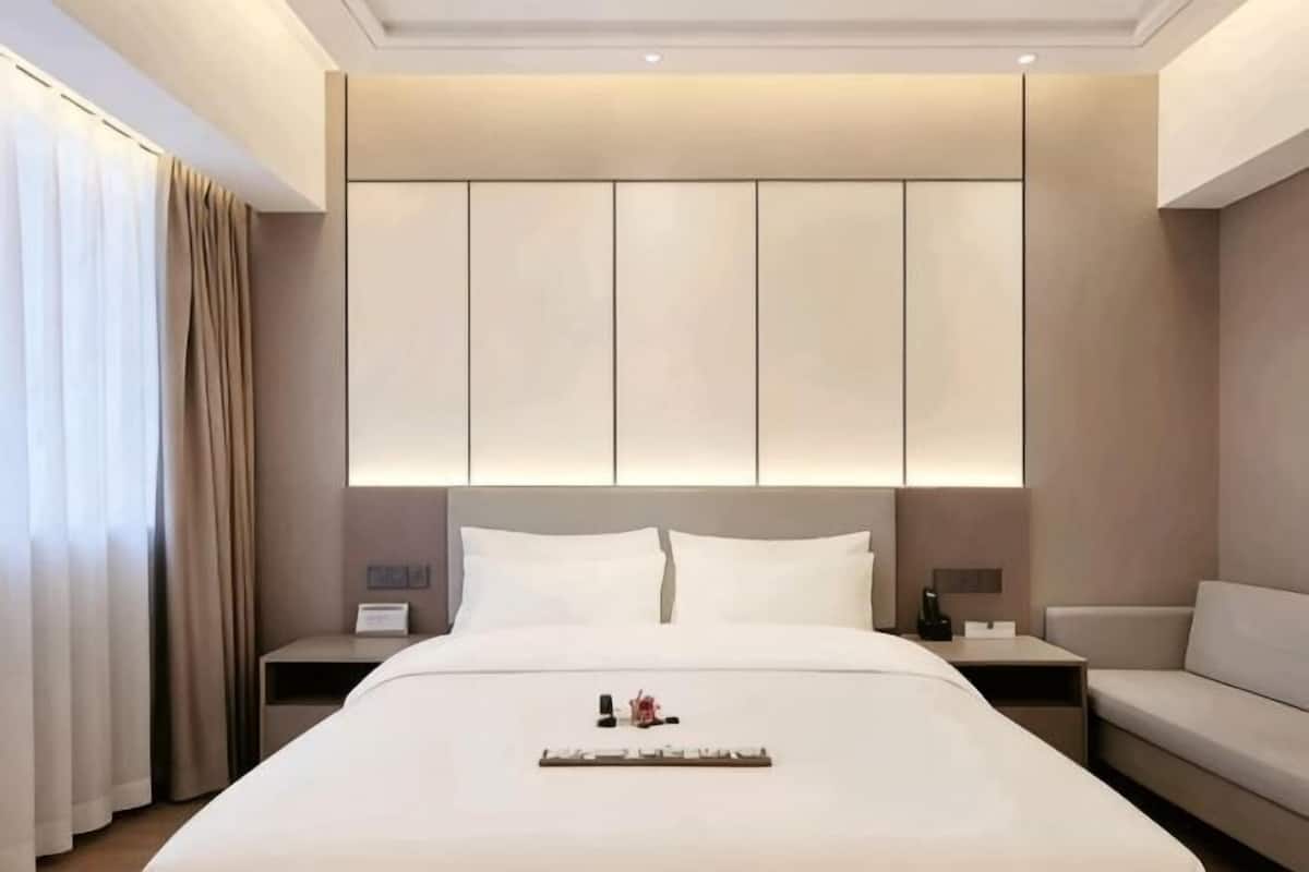Una camera d'albergo moderna con un letto grande, un comodino e un divano.