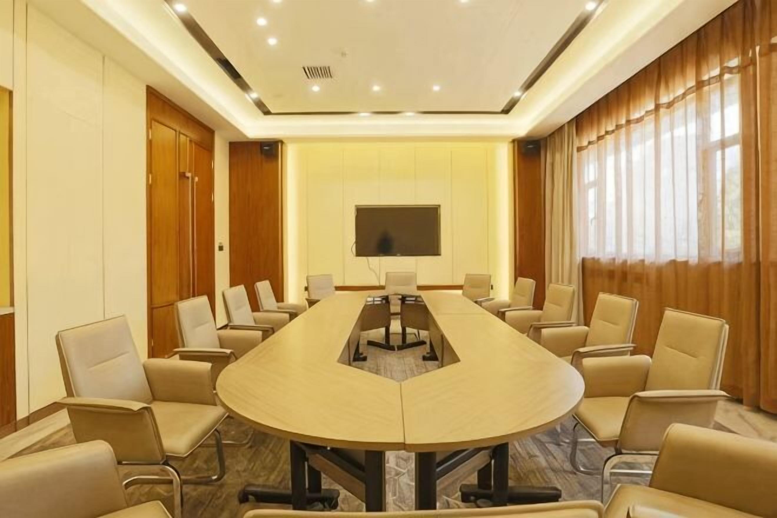 A conference room with a long table, chairs, a flat-screen TV, and a large window.