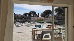 Eine moderne Außenpatio mit Lounge-Möbeln, einem Esstisch und Blick auf eine Wohngegend mit Bäumen und Gebäuden.