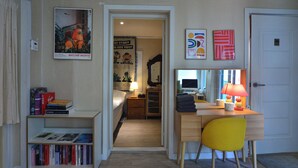 A compact hotel room with a bed, a desk with a chair, a bookshelf, and a door leading to a bathroom. - Helloworld guesthouse (Seoul)