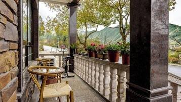 A balcony with wicker chairs, a table, and potted plants.