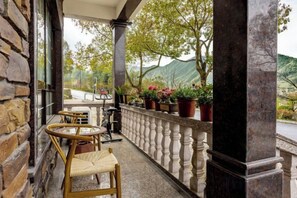 A balcony with wicker chairs, a table, and potted plants. - Anji Qile Farm (Anji)