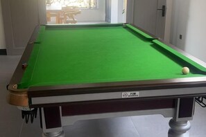 A pool table with a green felt surface, a cue ball, and a pool table logo. - Anji Qile Farm (Anji)