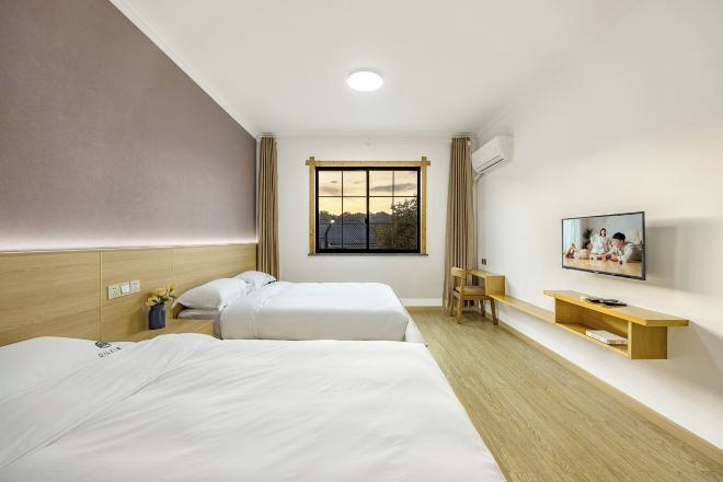 Een hotelkamer met twee bedden, een televisie, een bureau en een raam met uitzicht.
