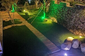 A well-lit garden pathway with a stone wall and a wooden fence. - Anji Qile Farm (Anji)