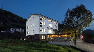 A multi-story hotel with a flat roof, a stone facade, and a well-lit entrance.