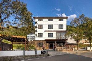 A two-story building with a flat roof, a covered entrance area, and a signboard. - Anji Qile Farm (Anji)