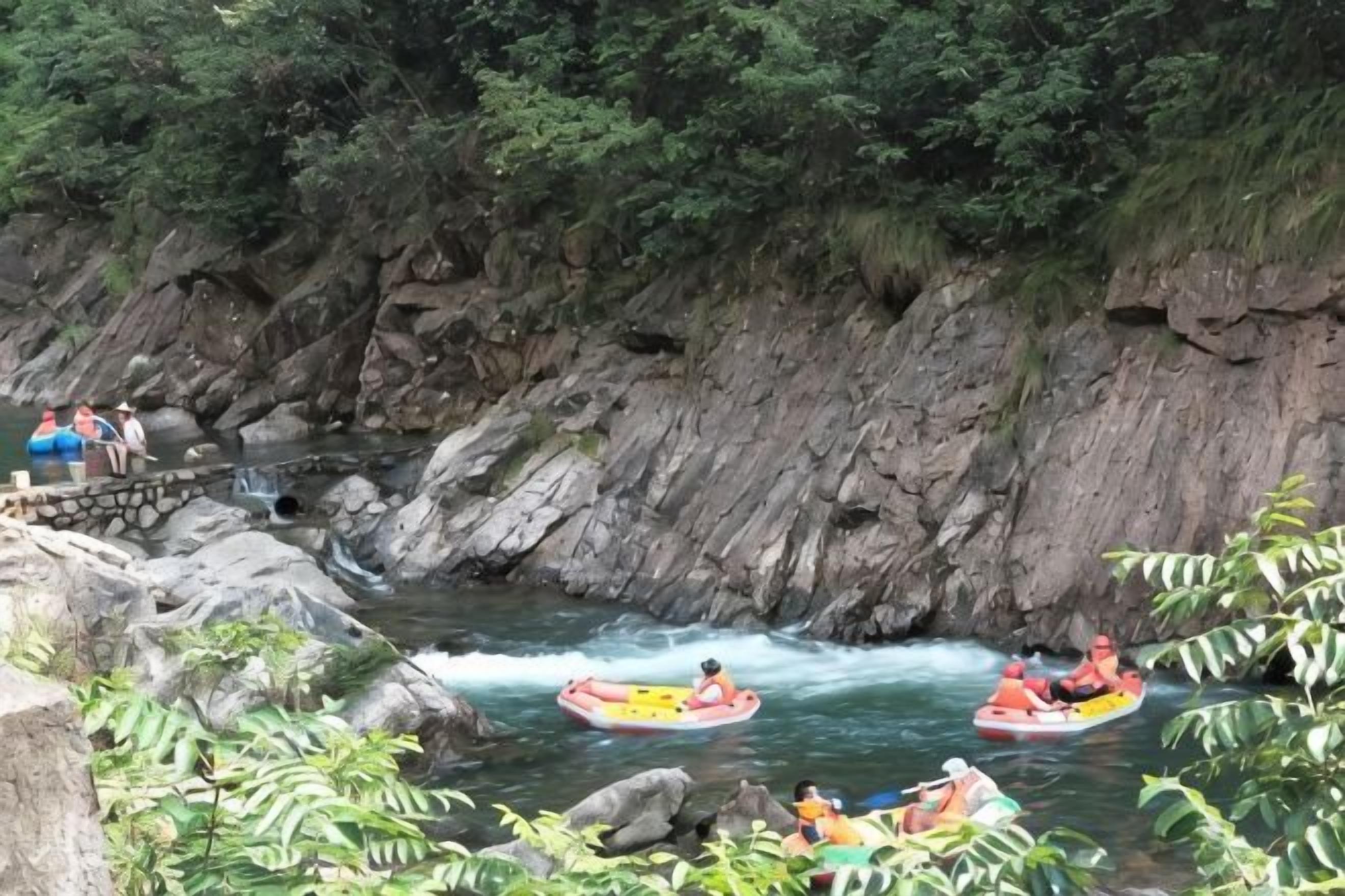 A river with people rafting and a bridge in the background.