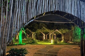 Una estructura en arco con un jardín en la parte inferior, que incluye un sendero y una iluminación verde.