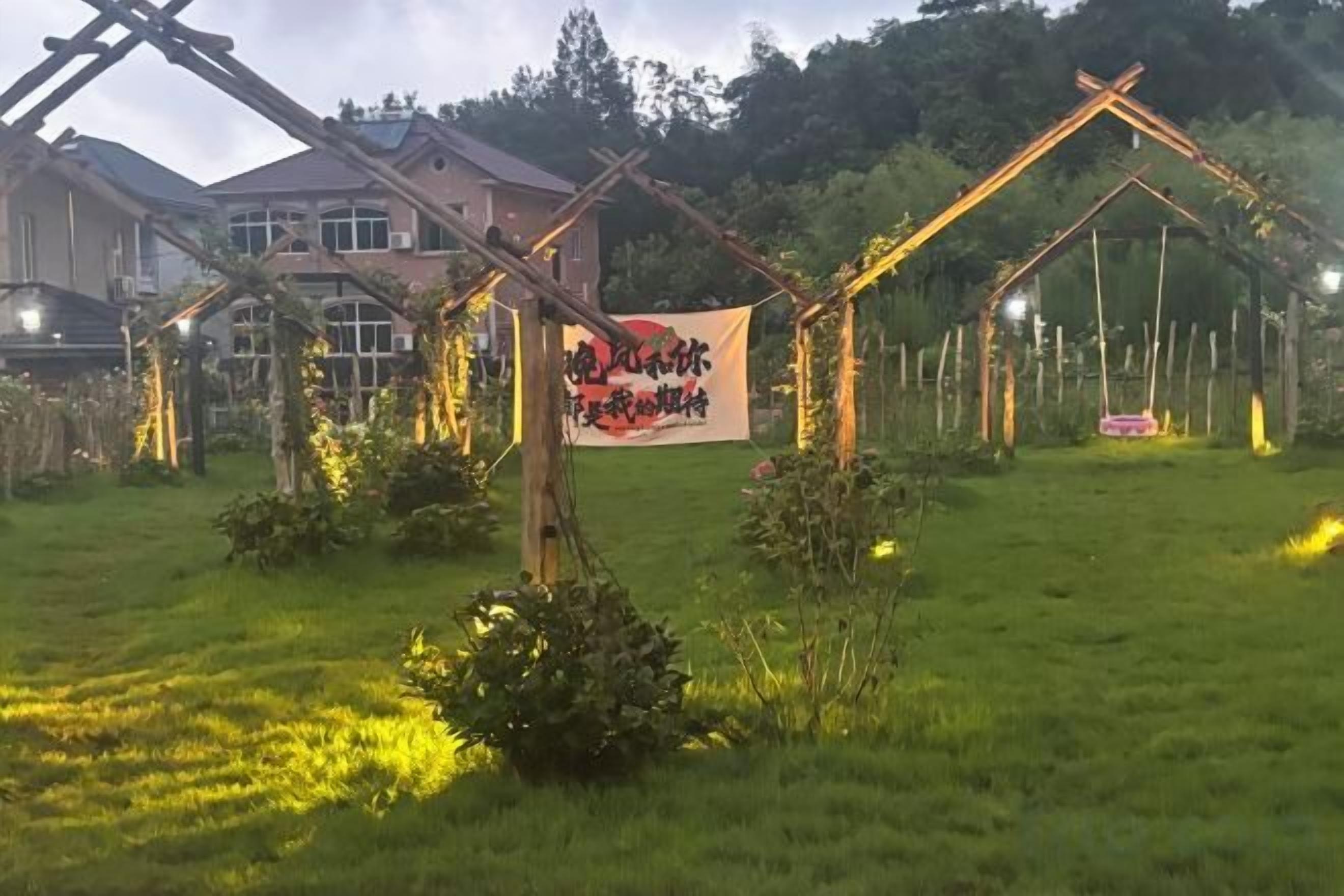 A garden with a wooden archway, a swing, and a banner with text.