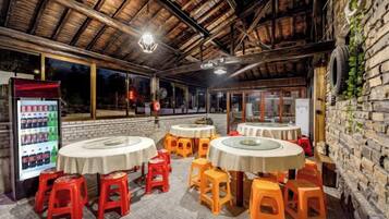 An outdoor dining area with round tables and stools, a beverage dispenser, and a brick wall.