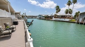 A waterfront property with a wooden deck, lounge chairs, and a view of the water. - Long Island Village 314 (Port Isabel)