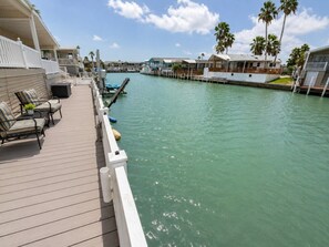 A waterfront property with a wooden deck, lounge chairs, and a view of the water. - Long Island Village 314 (Port Isabel)