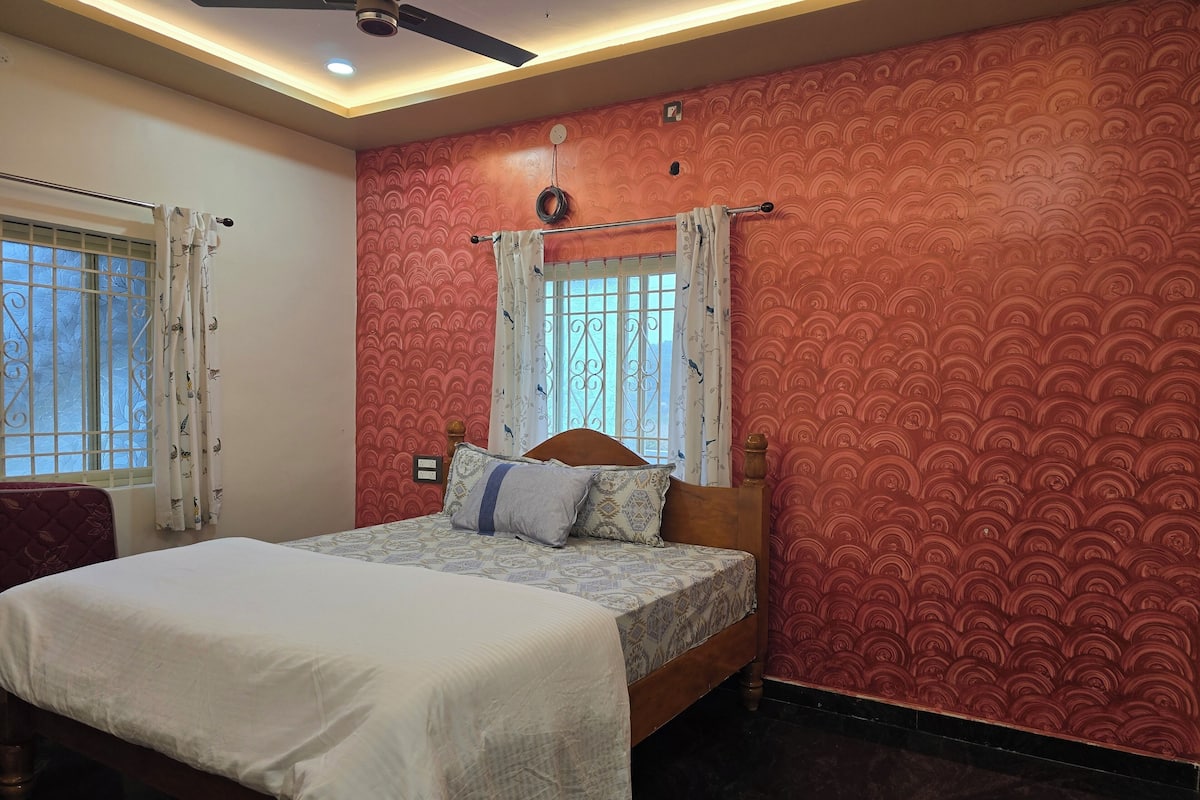 A bedroom with a bed, a ceiling fan, and patterned wallpaper.