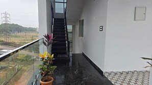 A modern building with a black marble floor, a staircase, and a potted plant on the balcony. - Lakshmi Villa (Hospet)