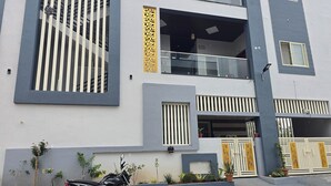 A modern two-story building with a balcony, a gated entrance, and a motorcycle parked in front. - Lakshmi Villa (Hospet)