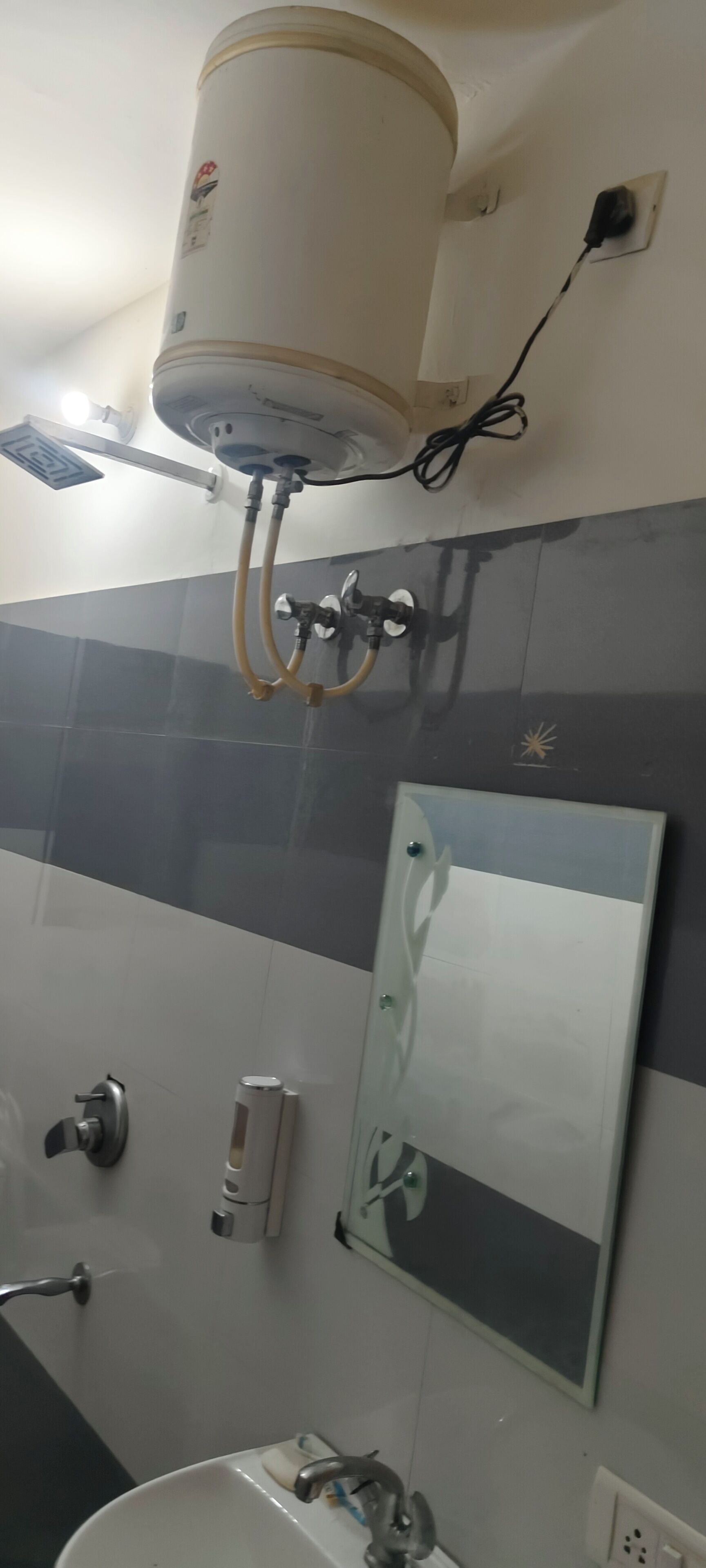 A bathroom with a white heater mounted on the wall, a mirror, a sink, and a towel rack.