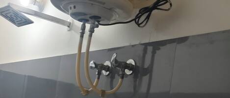A bathroom with a white heater mounted on the wall, a mirror, a sink, and a towel rack.