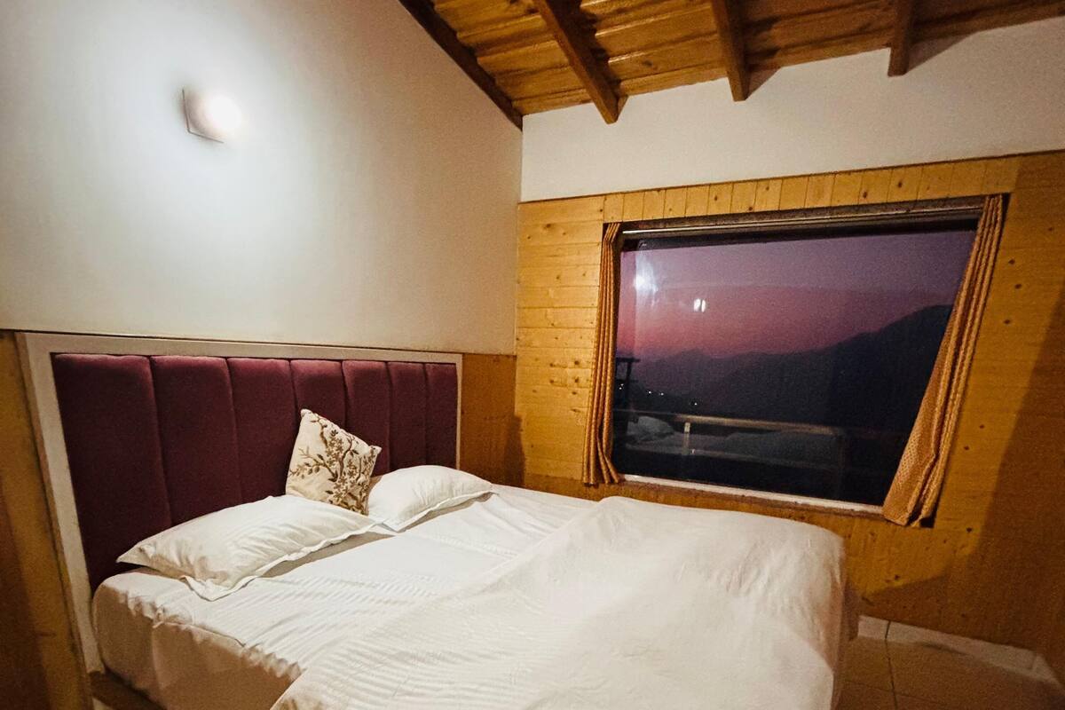 Un dormitorio con una cama, una ventana y techo de madera.