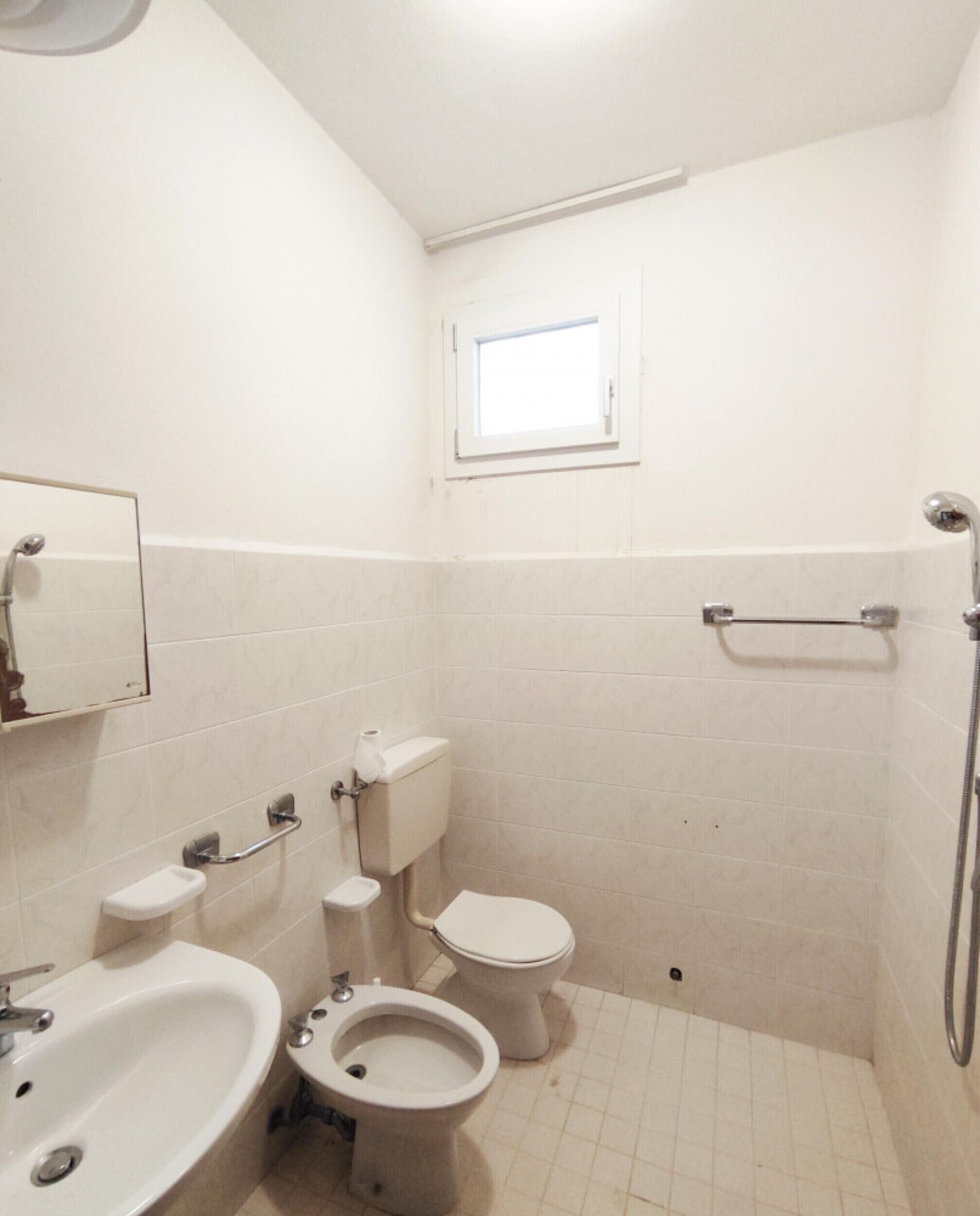 Un baño pequeño y sencillo con inodoro, bidé y lavamanos.