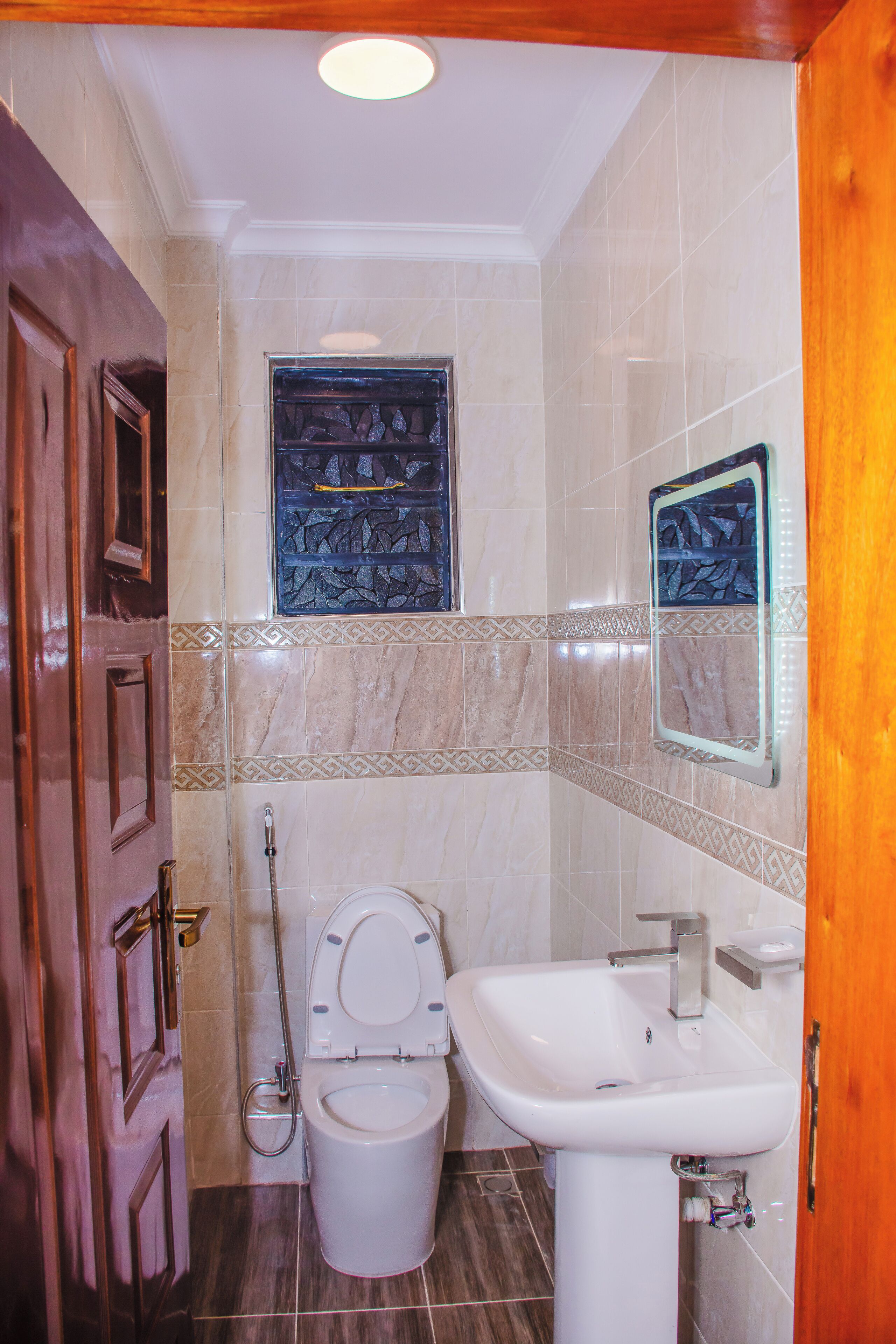 A bathroom with a toilet, sink, and decorative tiles.
