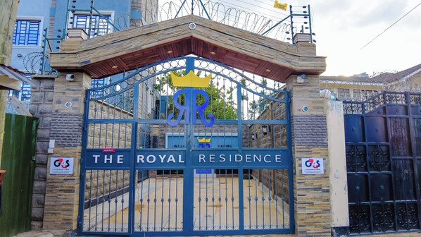 A gated entrance labeled "The Royal Residence" with a blue gate and a sign indicating "G4S" and "An Allied Universal Company."