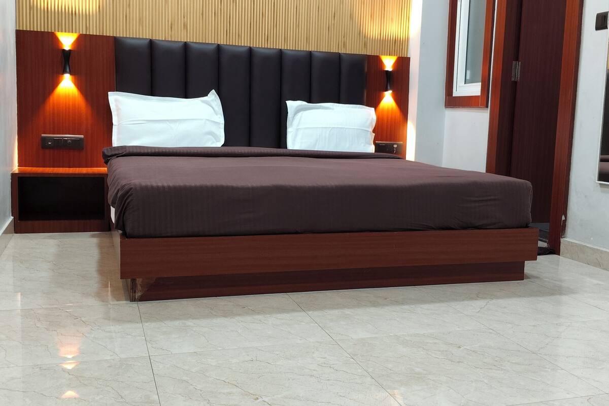 A modern hotel room with a large bed, wooden headboard, and bedside lamps.